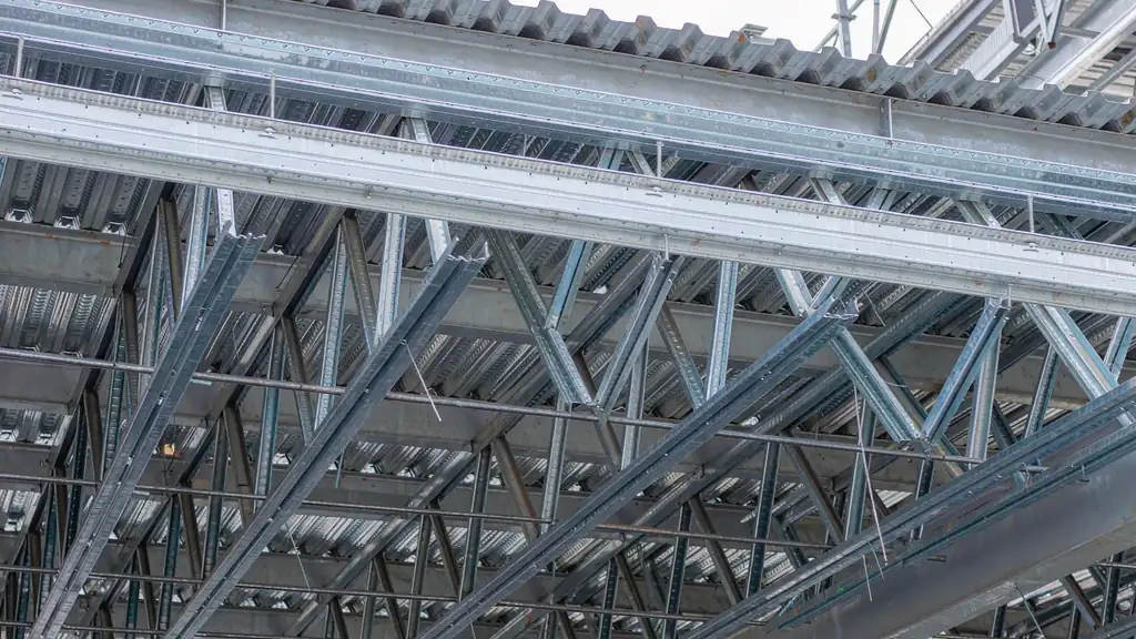 Underside of an industrial steel warehouse roof showing galvanised Z purlins with bridging struts between the purlin lines