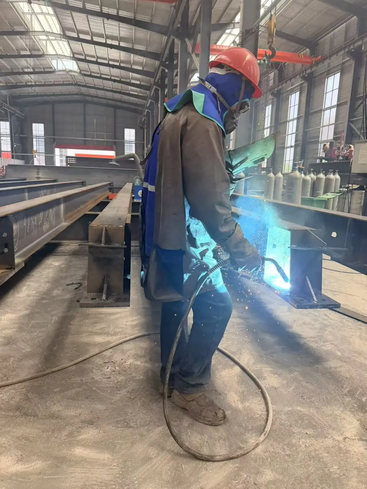 Certified welder performing submerged arc welding on steel beam