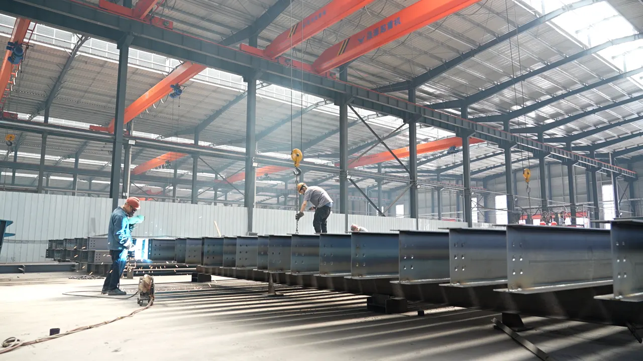 Welders fabricating long-span steel beams on the workshop floor